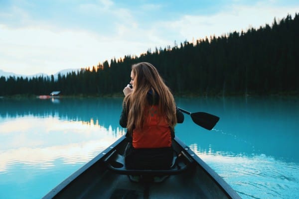 Image of a woman in the front of a canoe paddling